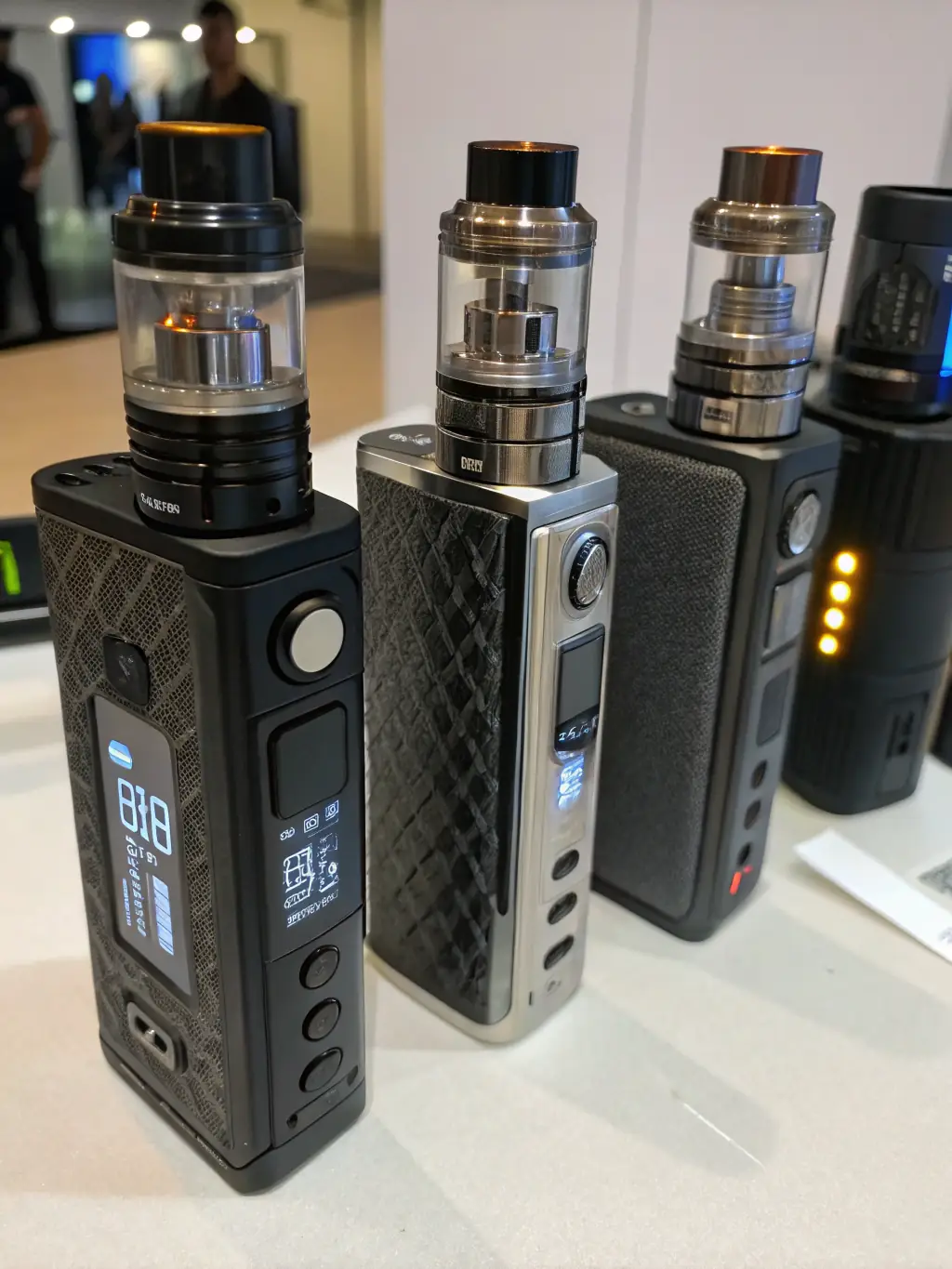 A professionally lit image displaying a selection of pre-designed vape mods and e-cigarettes, ready for branding. The background is a clean, modern studio setting, emphasizing the variety and quality of the ODM products.